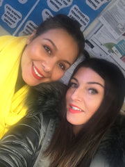 Two ladies smiling with positive quotes on a wall behind them
